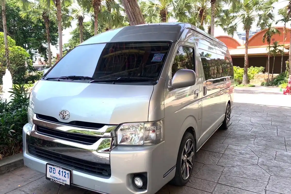 A Minivan parked on a paved hotel driveway under palm trees, seen from the front and slightly to the side.
