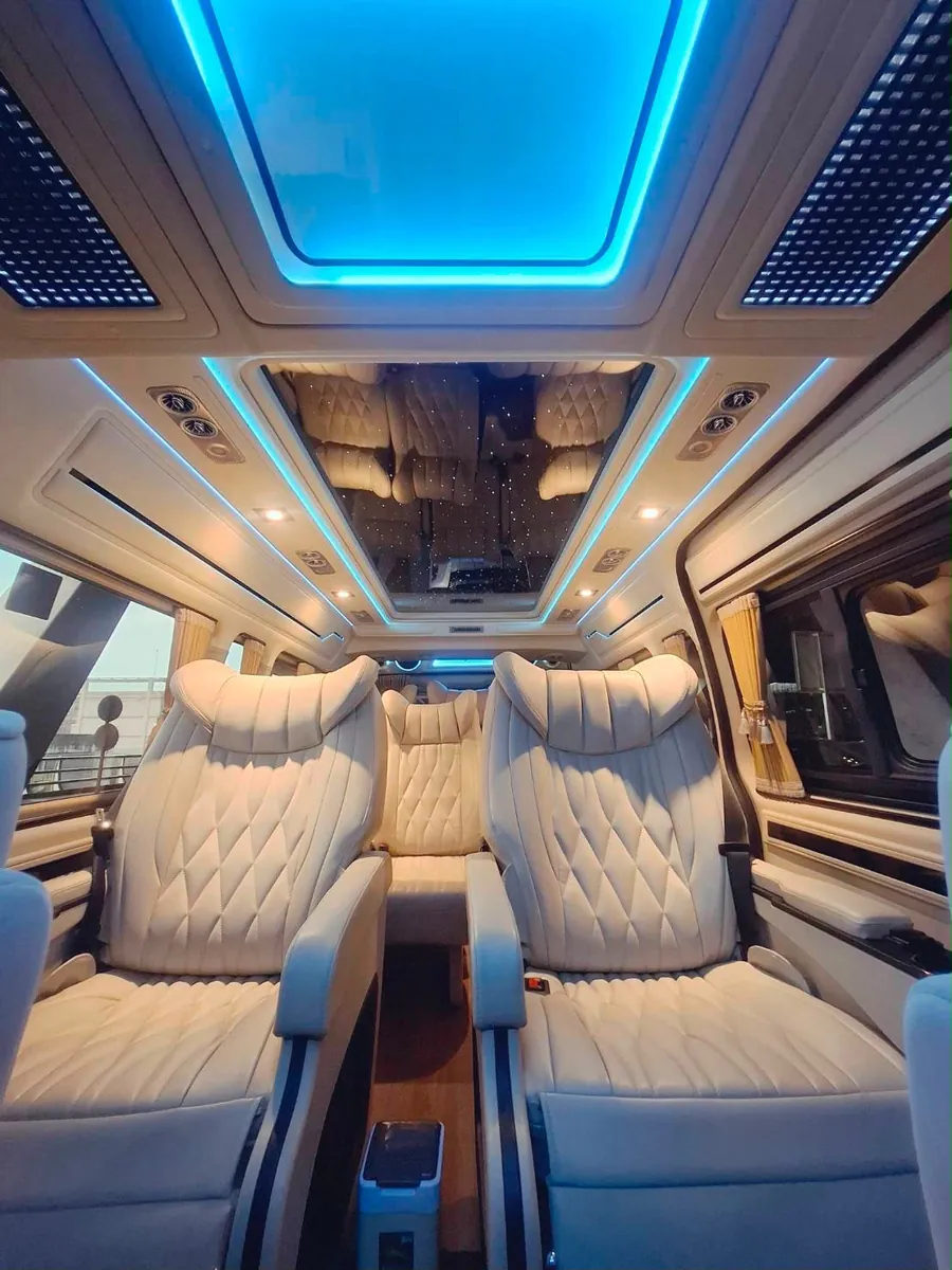 A VIP Minivan cabin seen along the centre aisle: a single reclining chair on either side of the aisle, which runs the length of the passenger compartment.